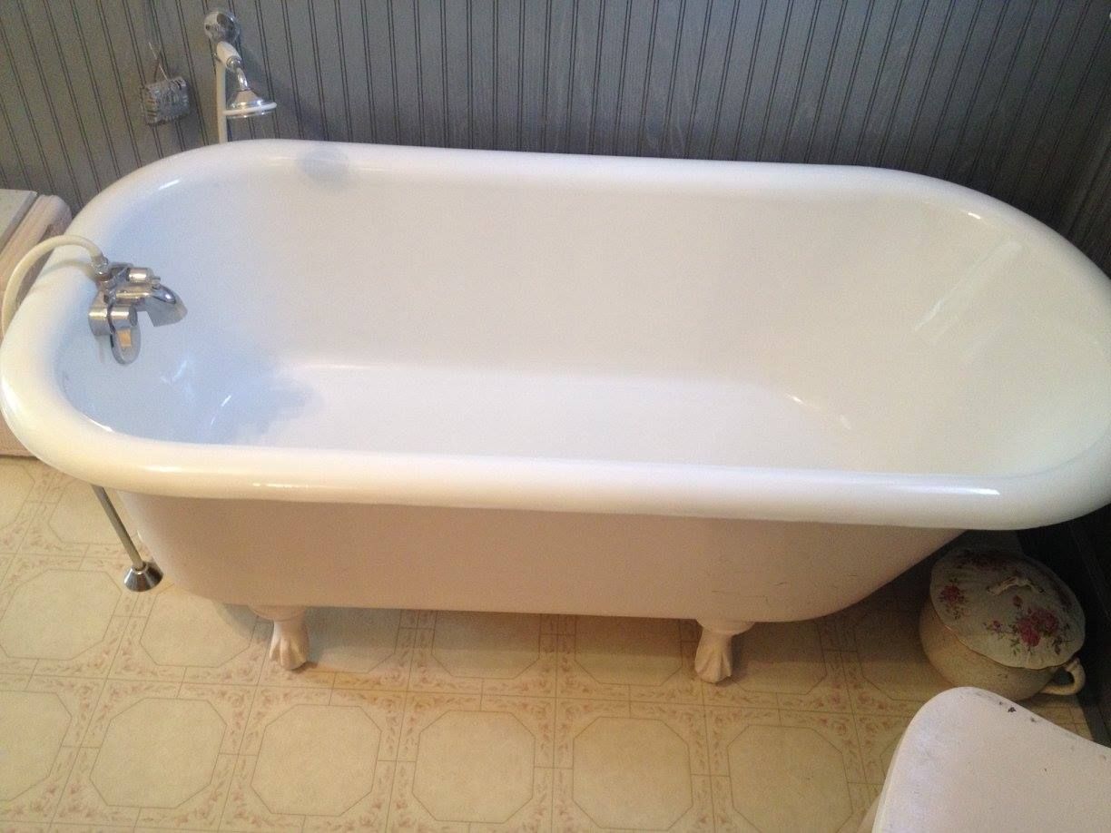 A white bathtub is sitting in a bathroom next to a toilet.