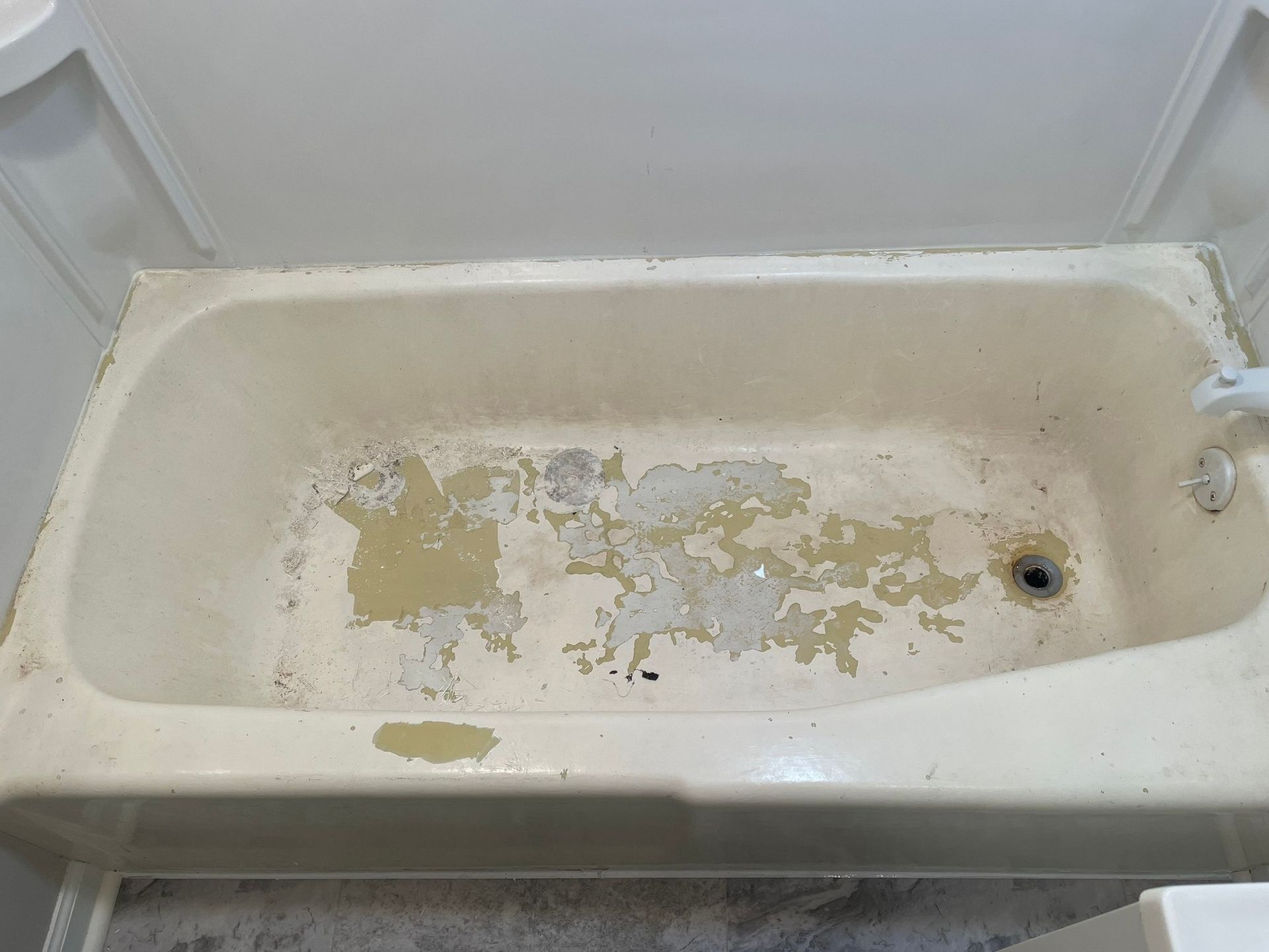 A bathtub in a bathroom with peeling paint on it.