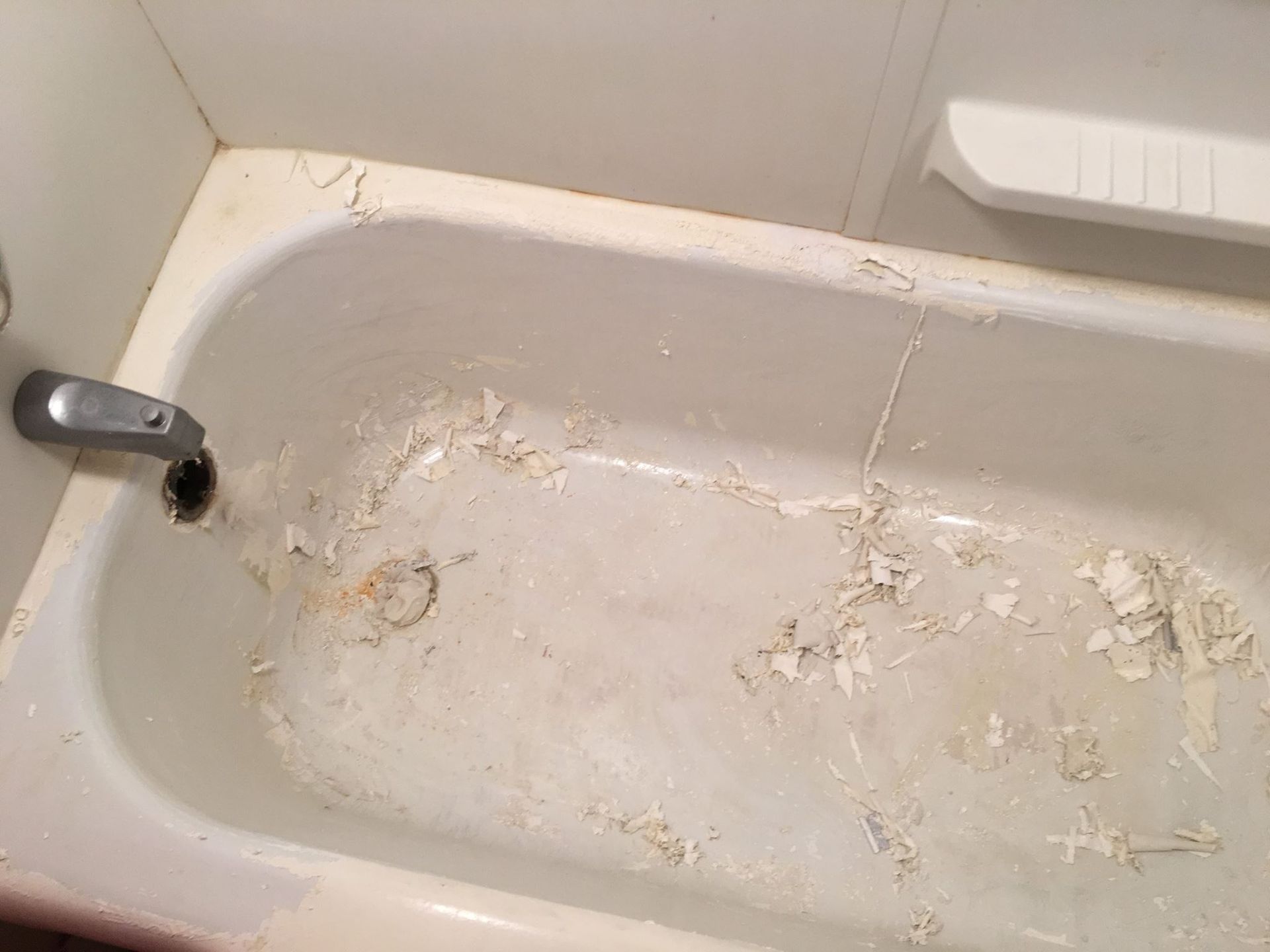 A dirty bathtub in a bathroom with a faucet.