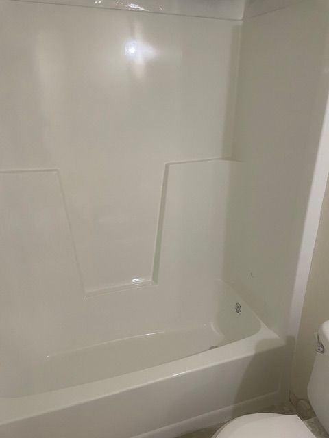 There is a bathtub in the bathroom next to a toilet.