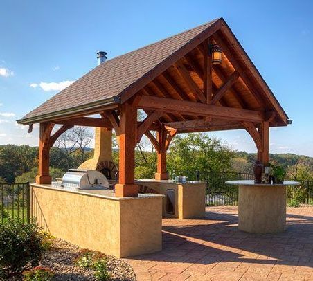 A wooden gazebo with a grill underneath it