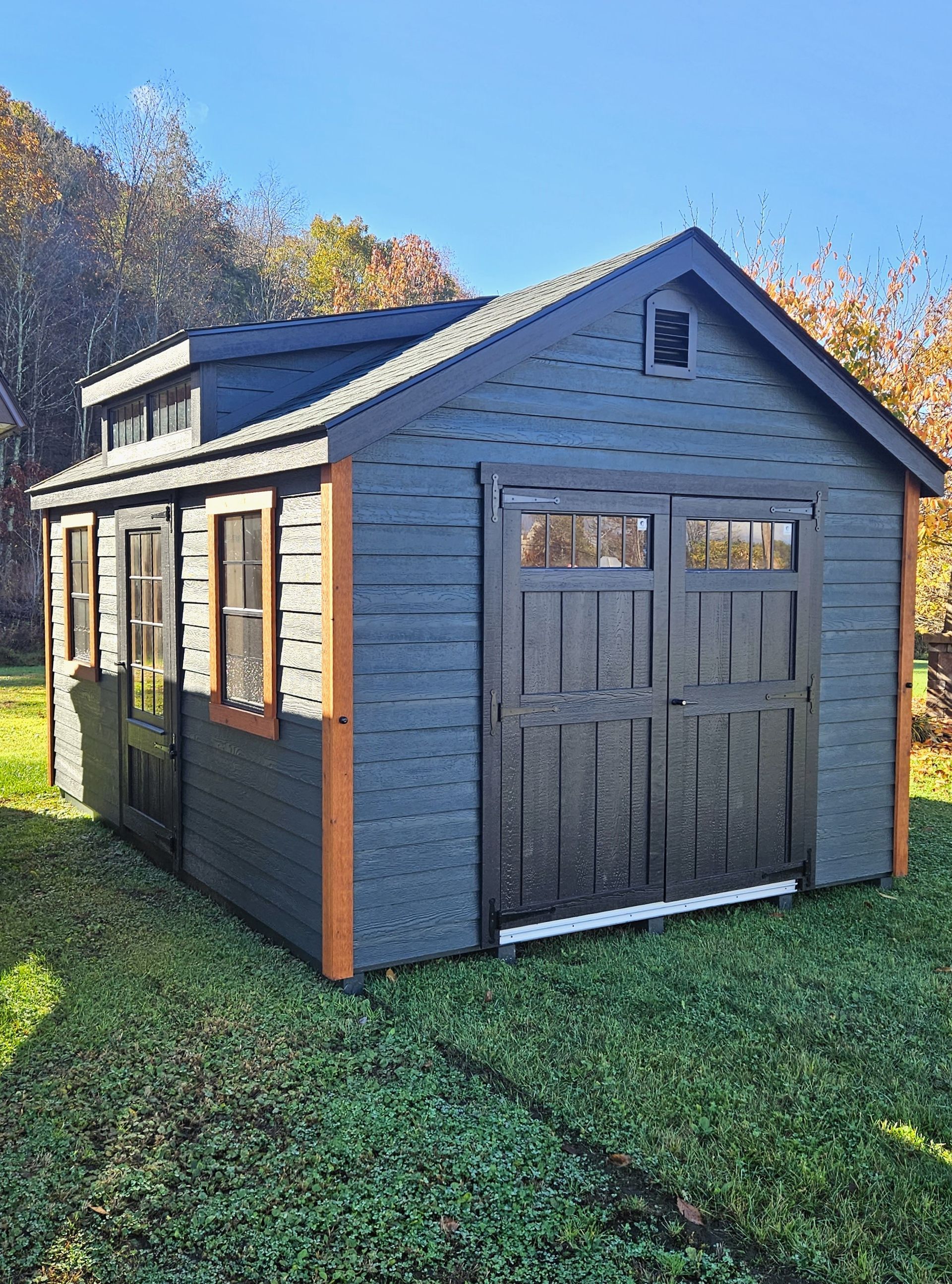 A small shed with a garage door is sitting on top of a lush green field.