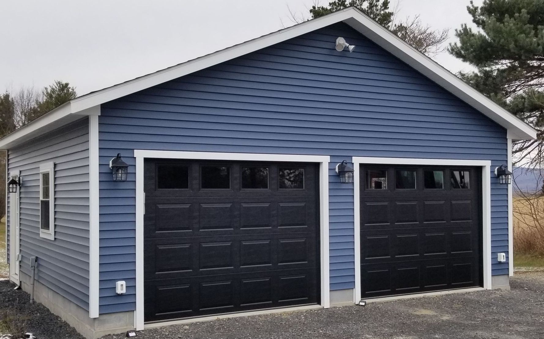 A blue garage with two black garage doors and a white trim