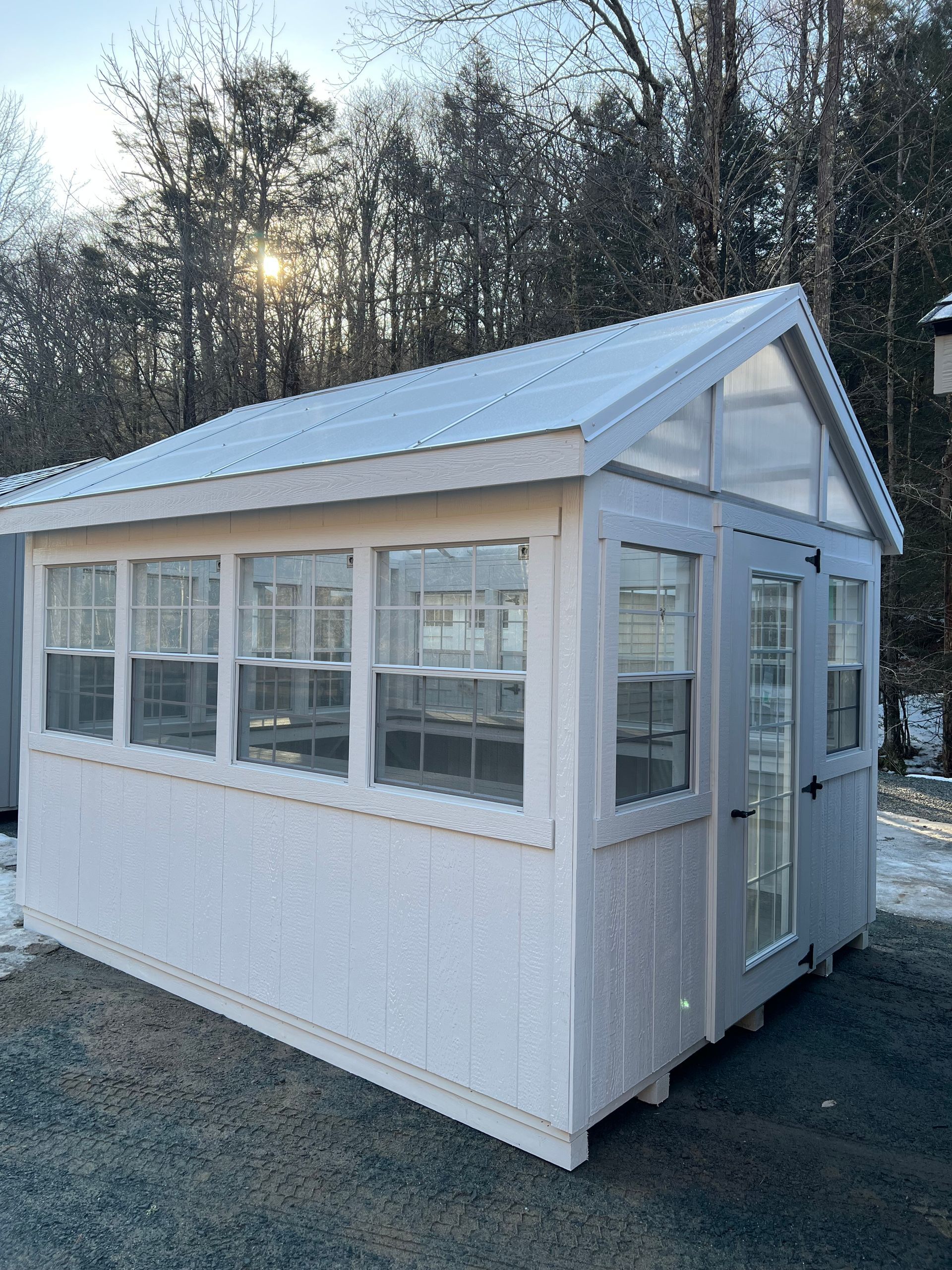 A white shed with a greenhouse attached to it.