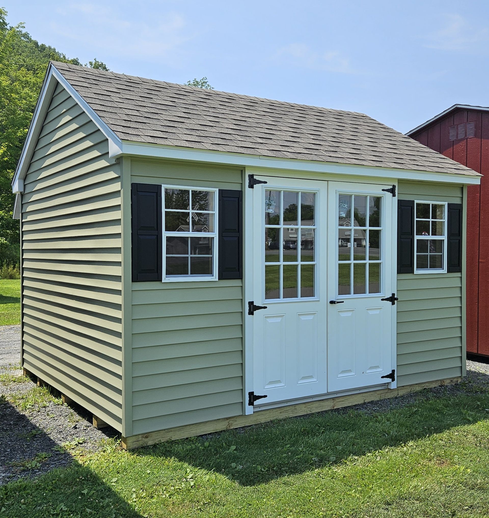 A green shed with white doors and black shutters