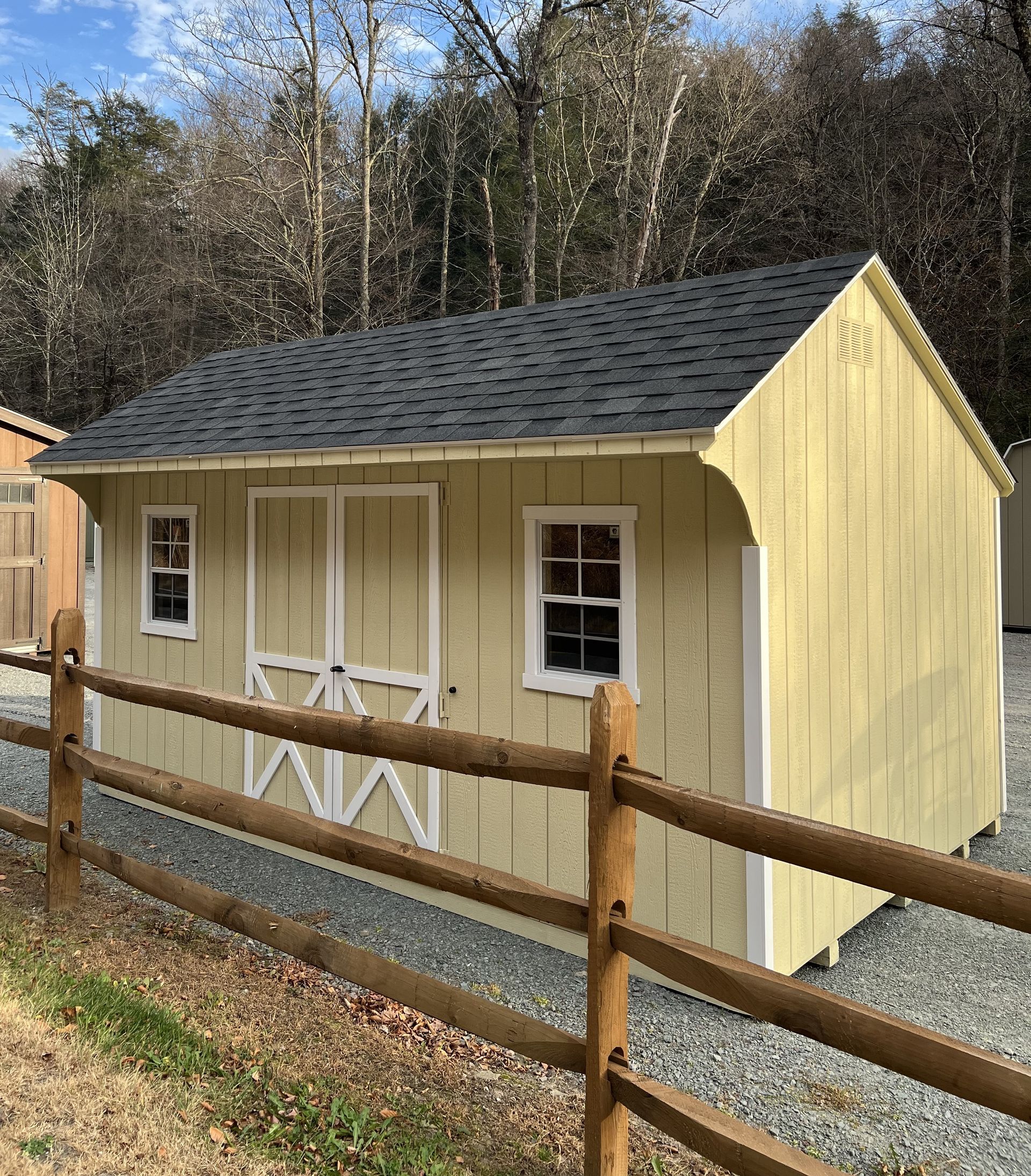 A yellow shed with a wooden fence around it.