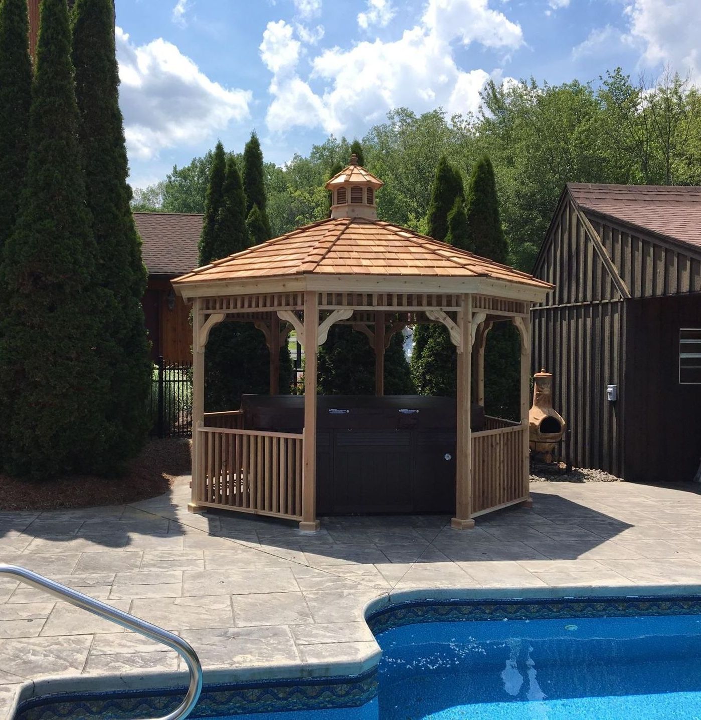 A wooden gazebo sits next to a swimming pool