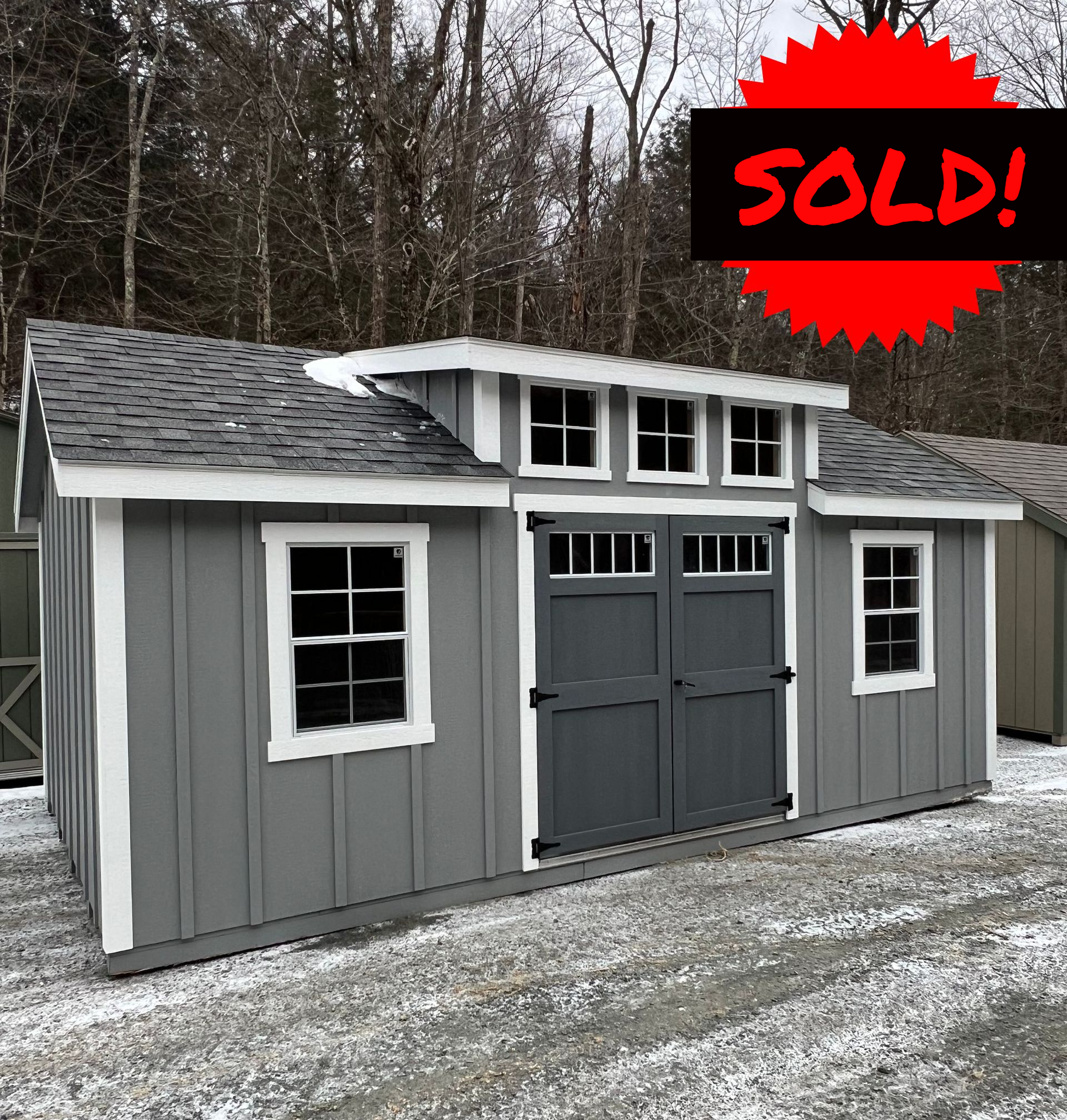 A gray and white shed with a red sticker that says `` new features ''.
