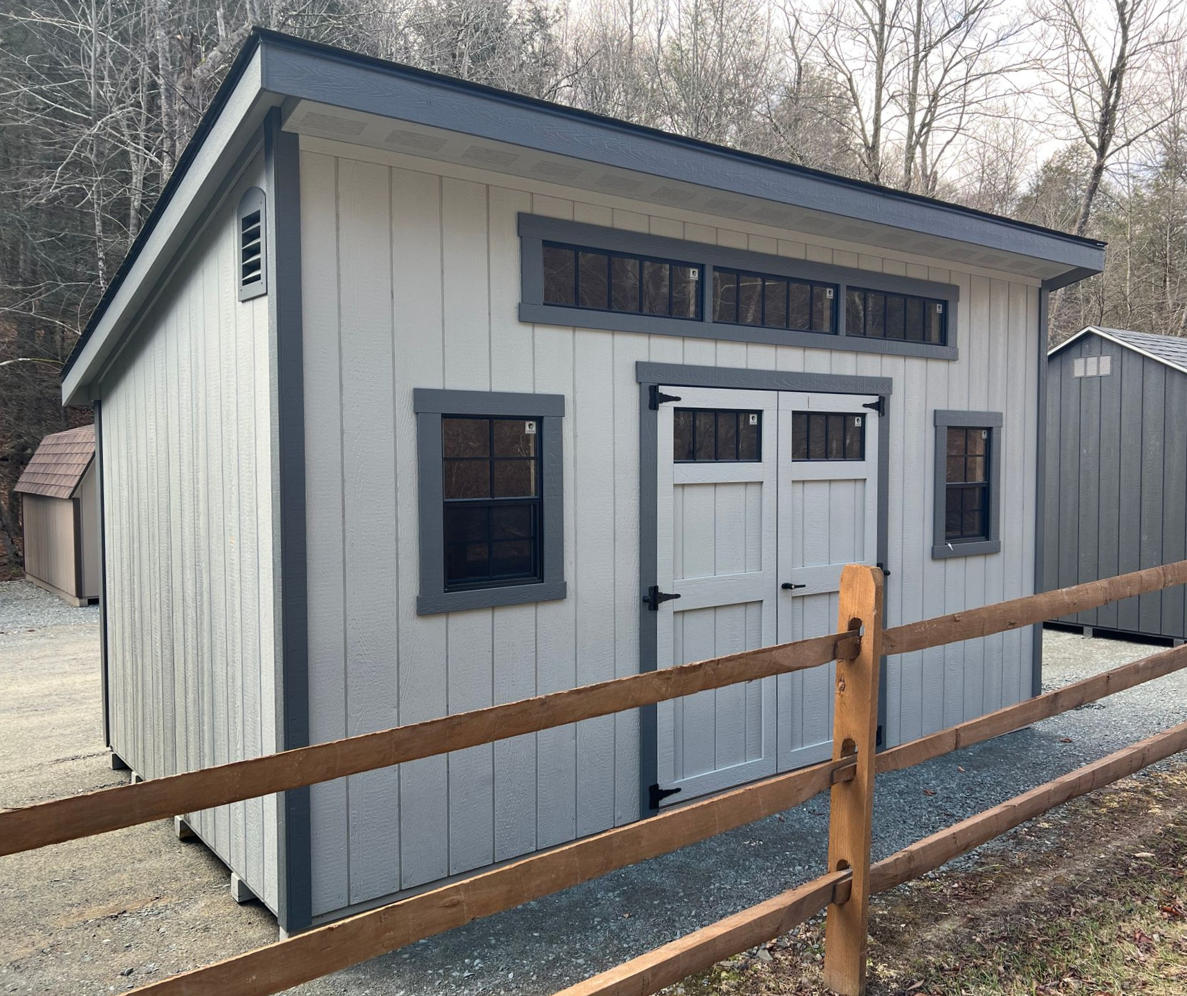 A small shed with a wooden fence around it.