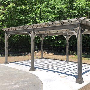 A wooden pergola is sitting on top of a concrete patio.
