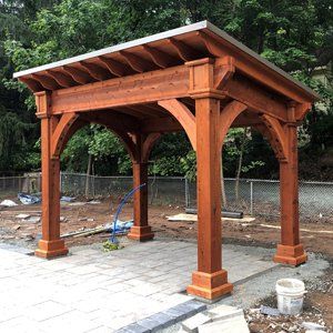 A wooden gazebo is sitting on top of a brick patio.