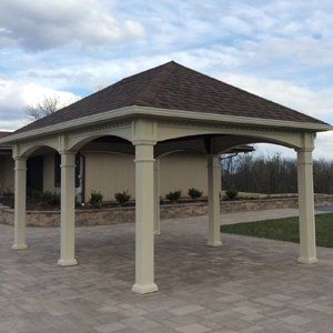 A white pavilion with a brown roof is in front of a house.