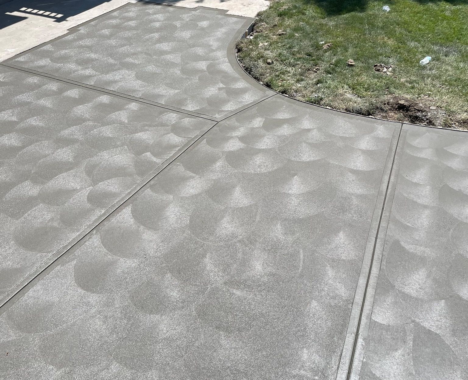 A concrete driveway leading to a garage next to a house.