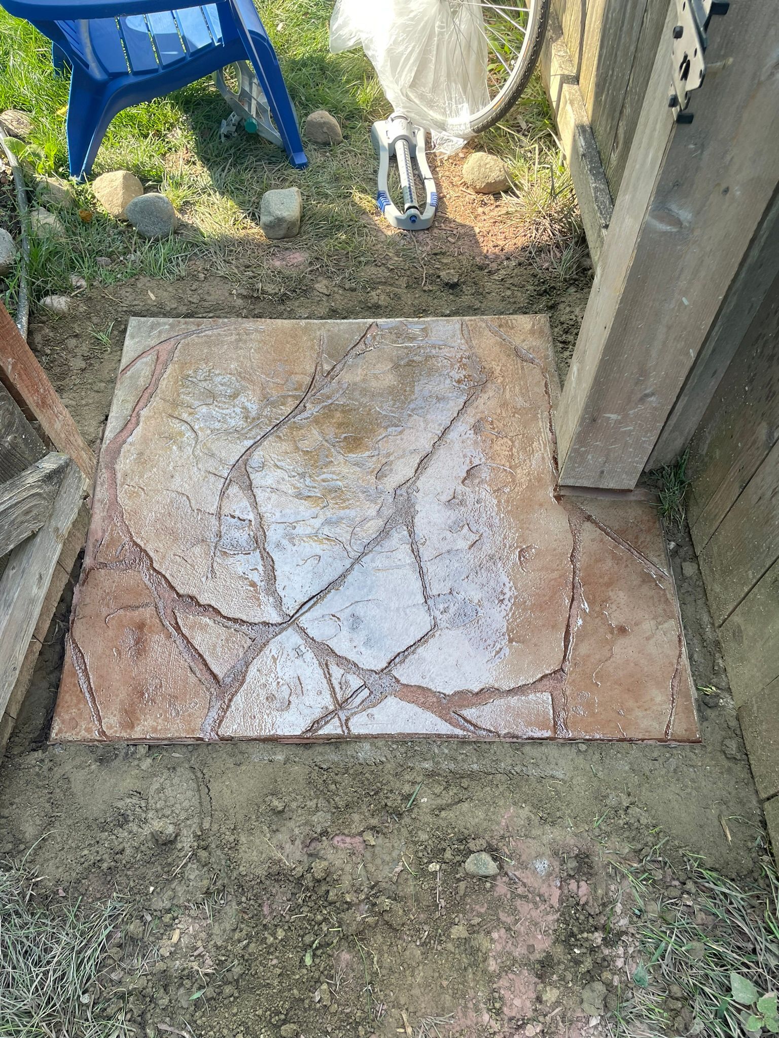 A blue chair is sitting in the grass next to a stone walkway.