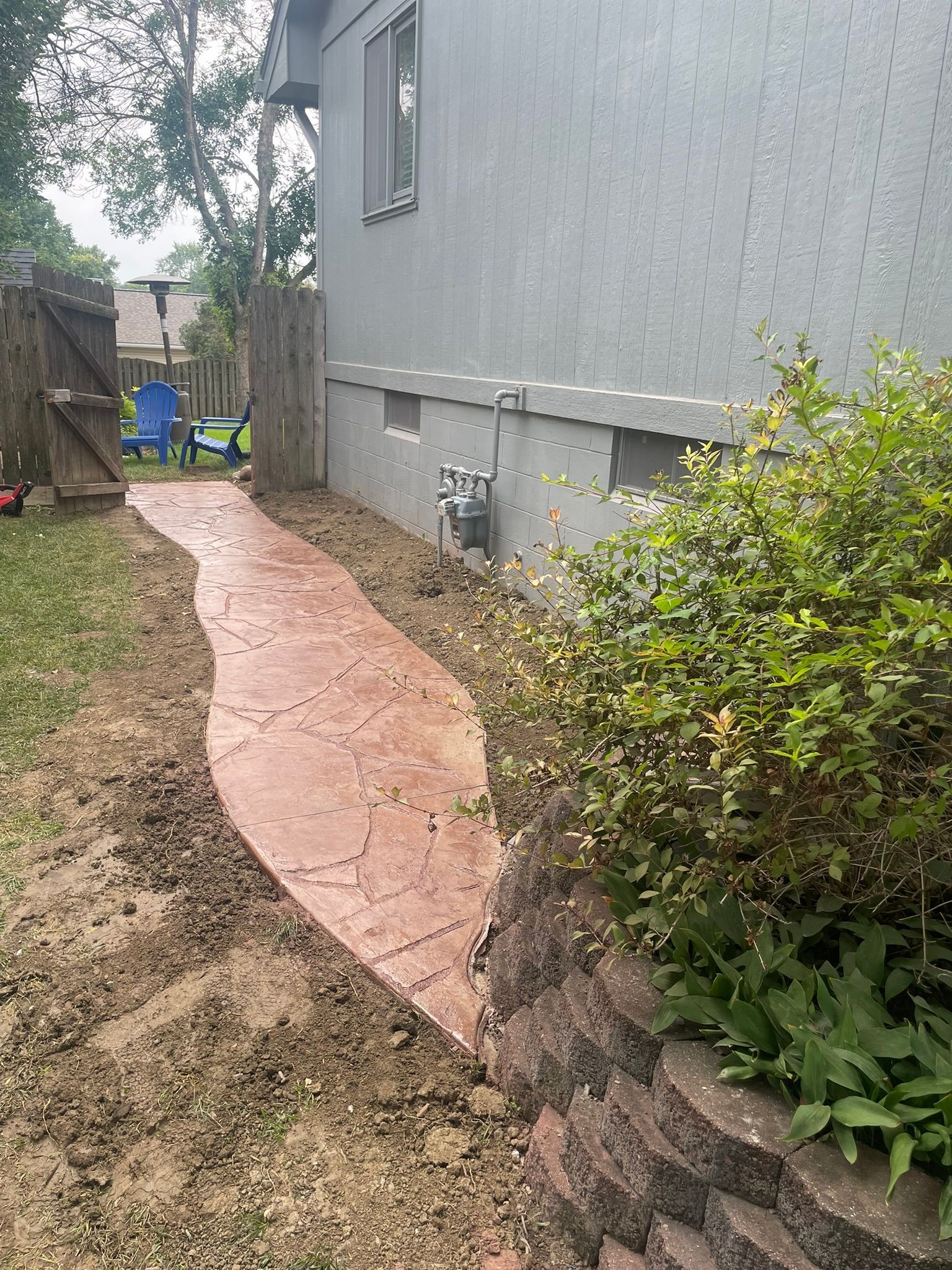 A concrete walkway leading to a house in a backyard.