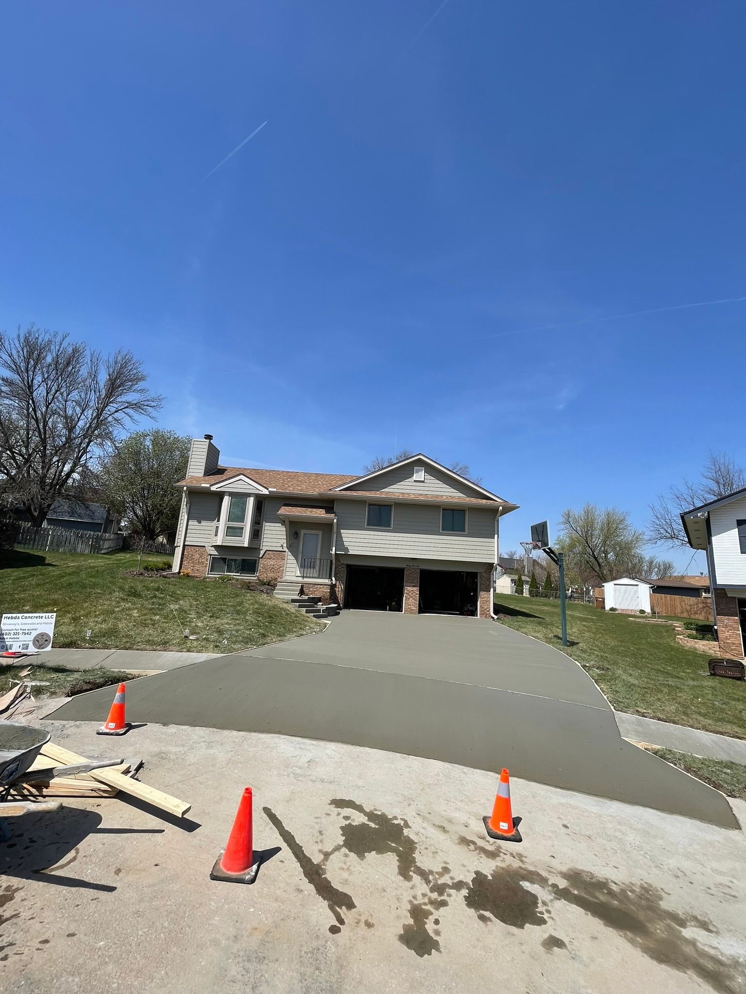 A concrete driveway is being installed in front of a house.