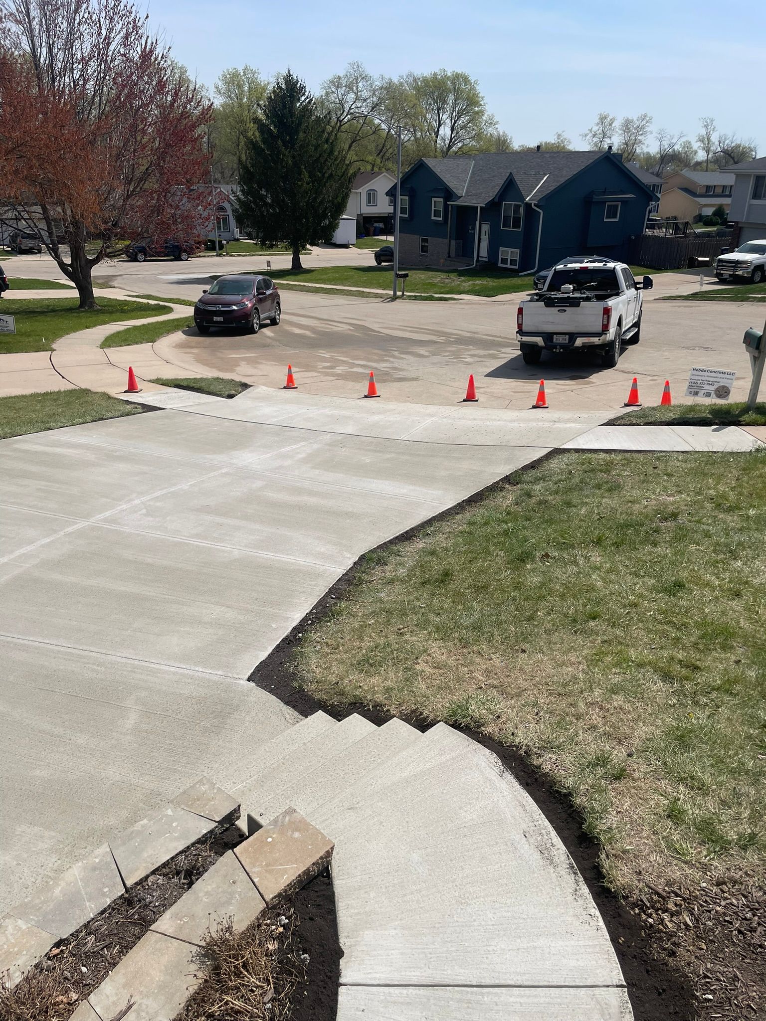 A white truck is parked on the side of the road next to a sidewalk.