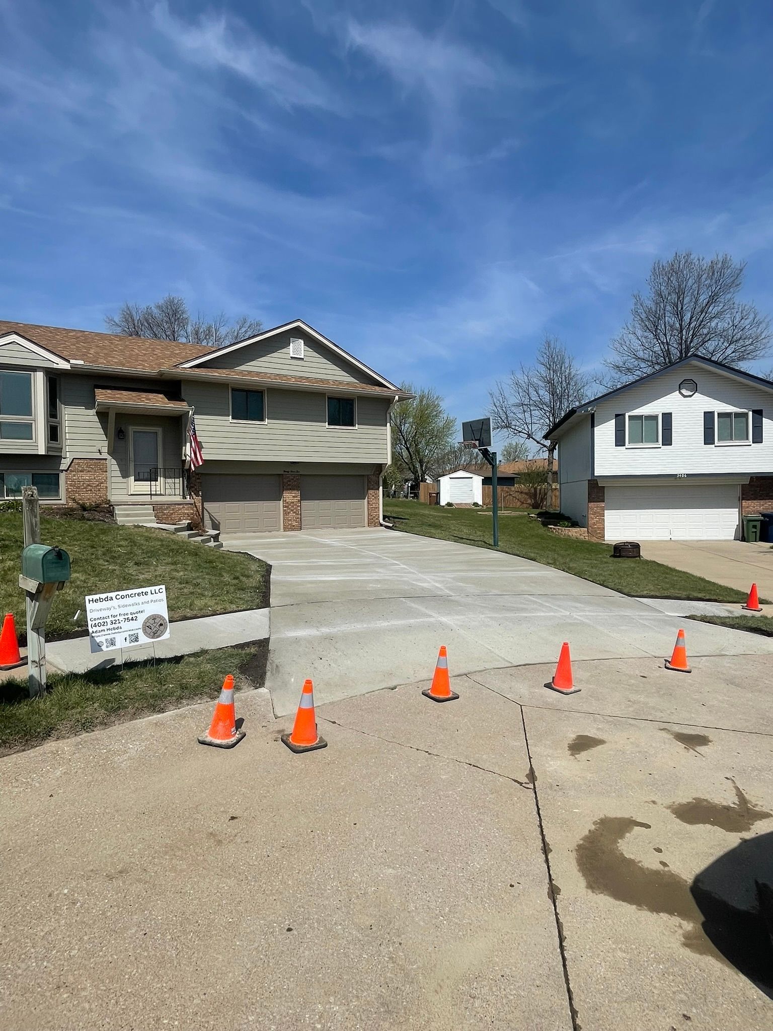 A concrete driveway with orange traffic cones in front of a house.