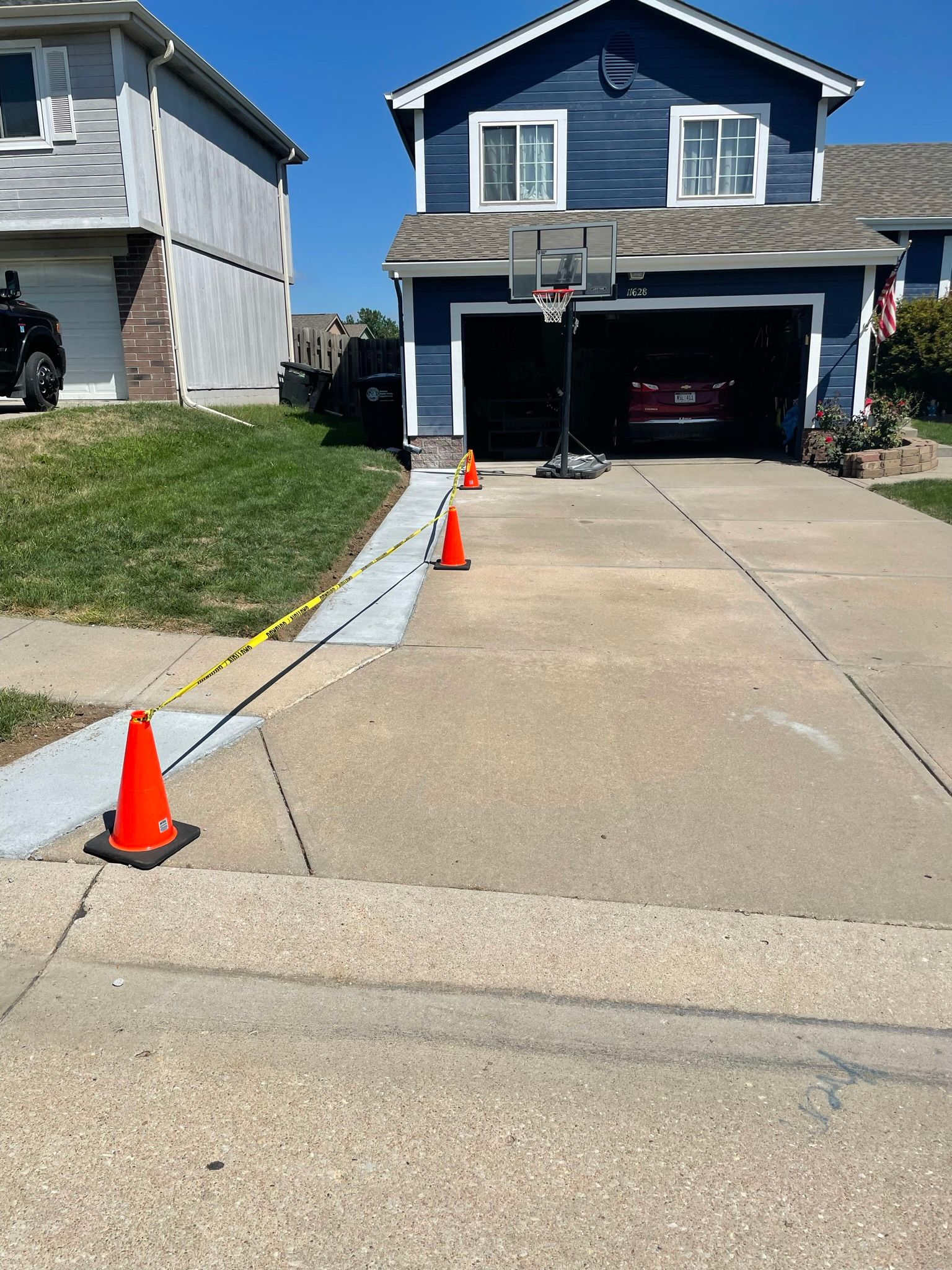 A basketball hoop is in the driveway of a house.