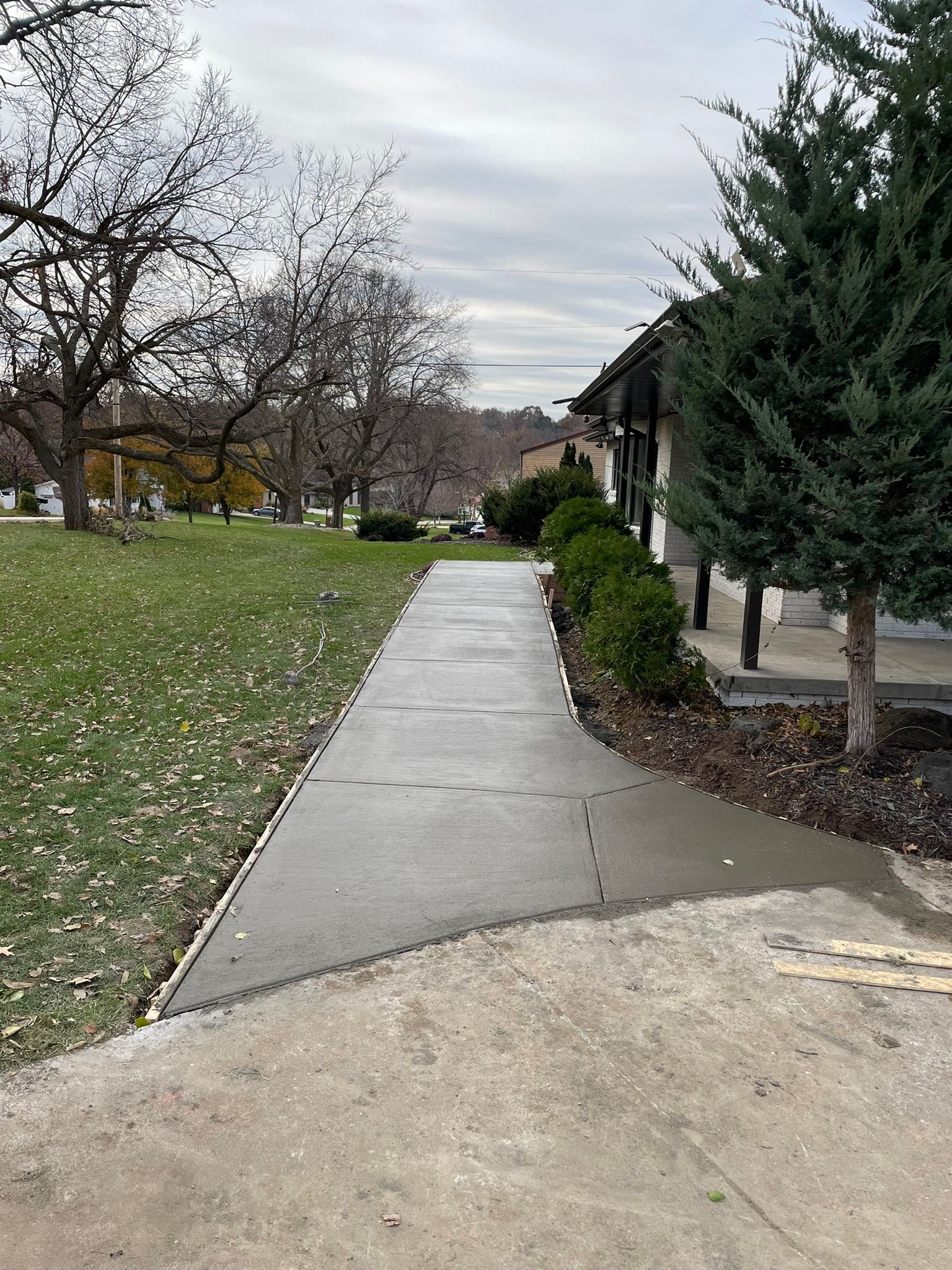 A concrete walkway leading to a house in a park.