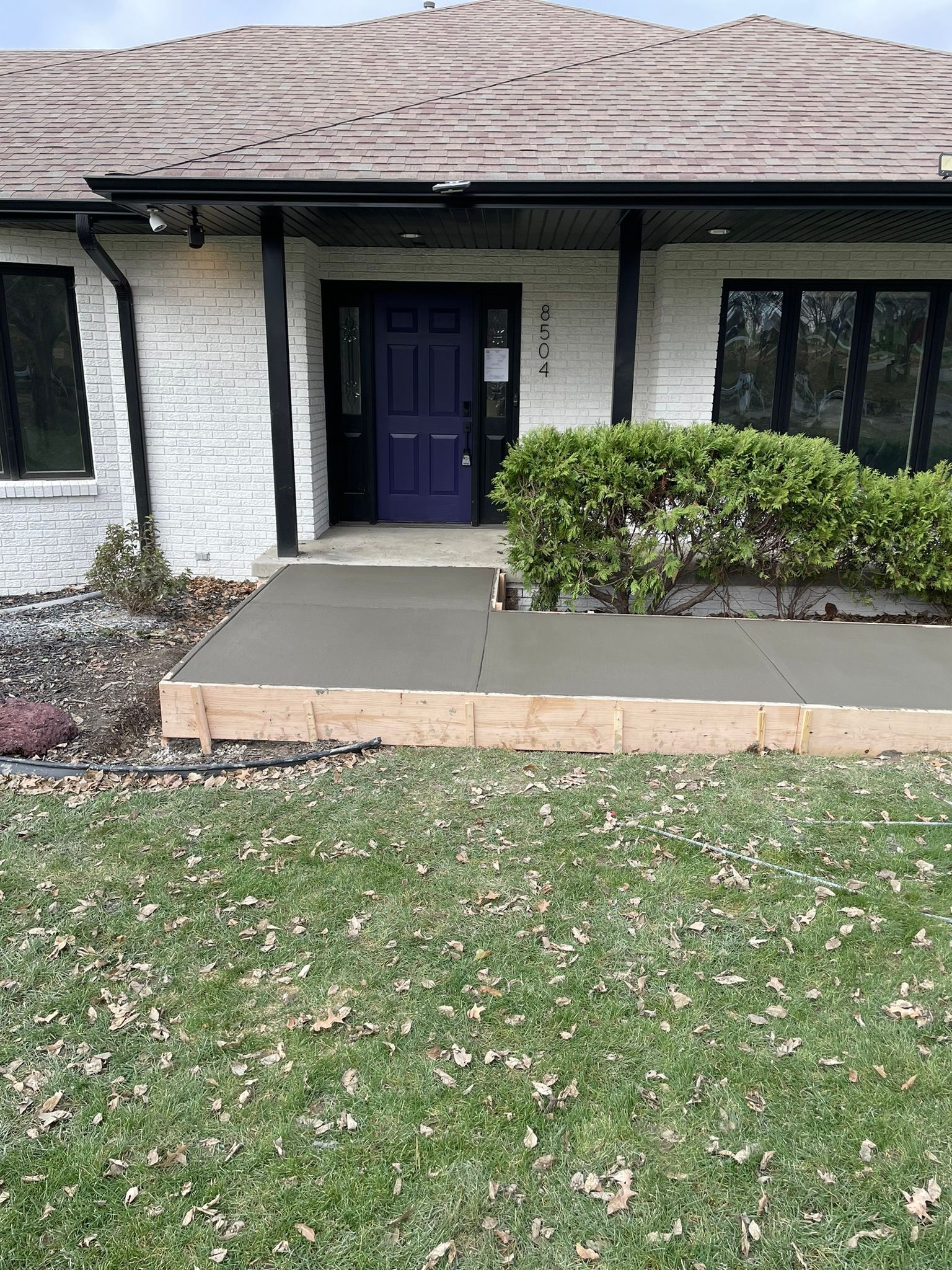 A white house with a blue door and a concrete walkway in front of it.