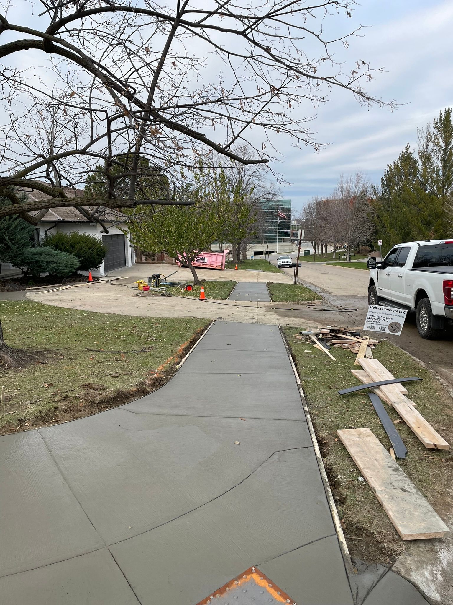 A white truck is parked on the side of a concrete driveway.