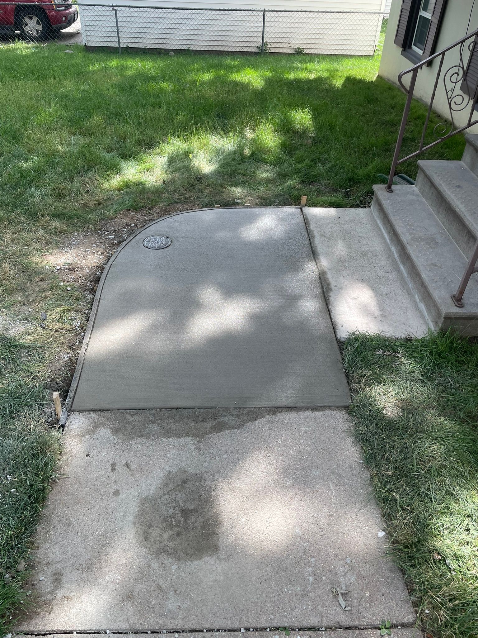 A concrete sidewalk with steps leading to a house.
