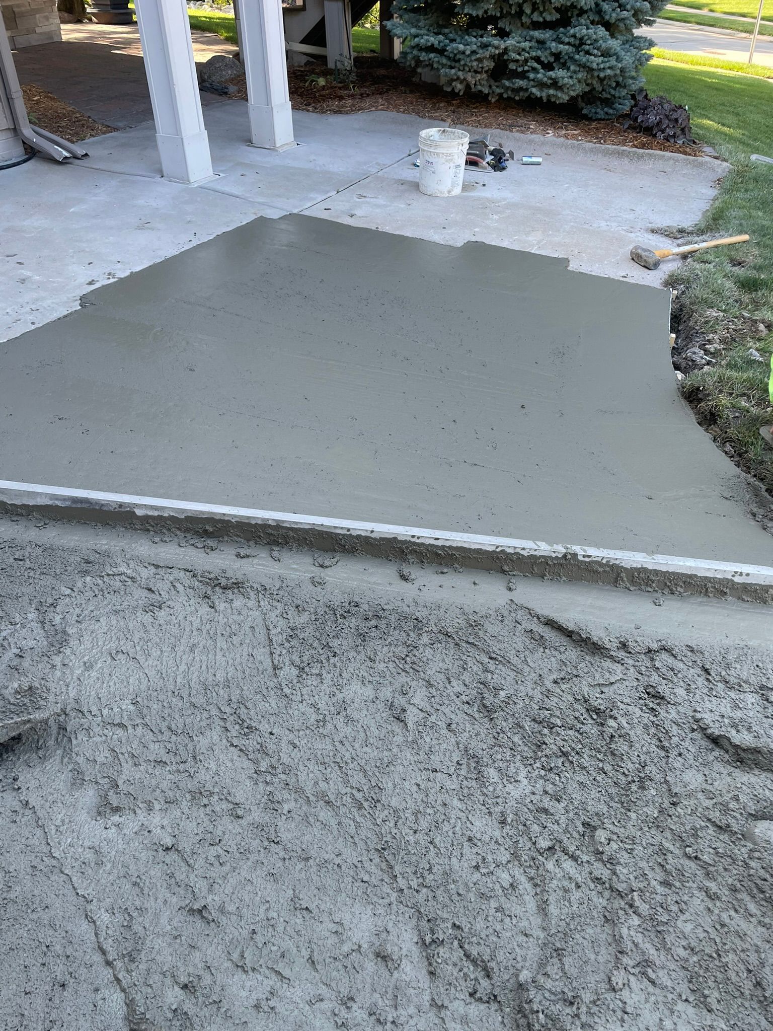 A bucket of concrete is sitting on top of a pile of concrete.