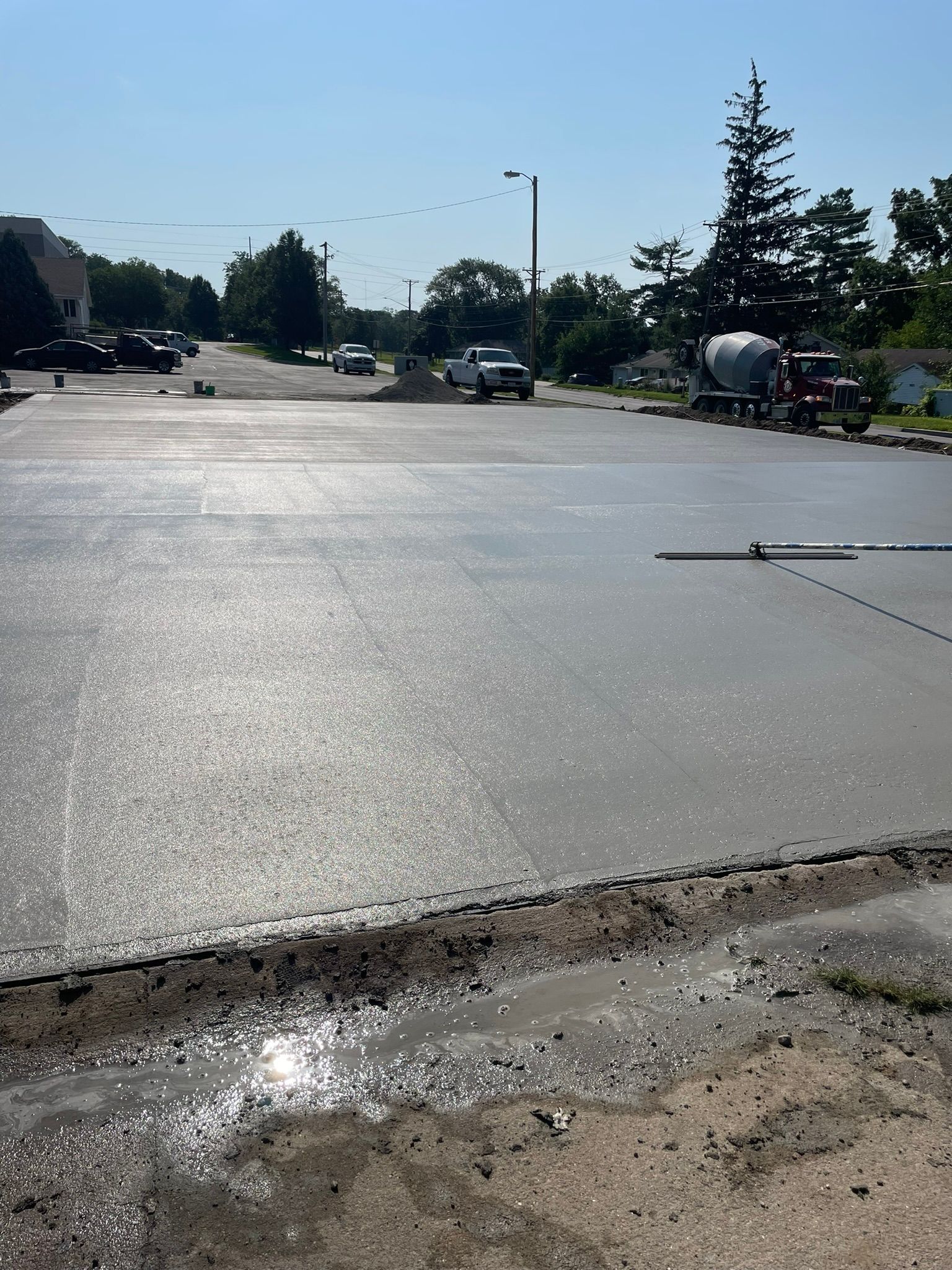 A concrete driveway is being poured in a parking lot.