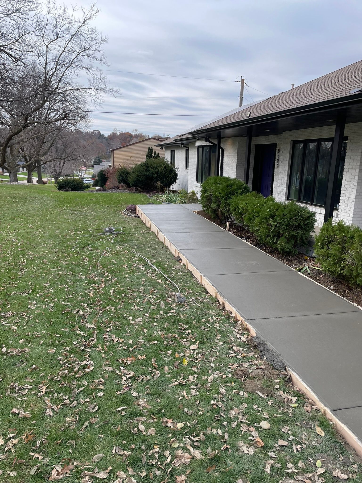 A concrete walkway leading to a house in a grassy area.