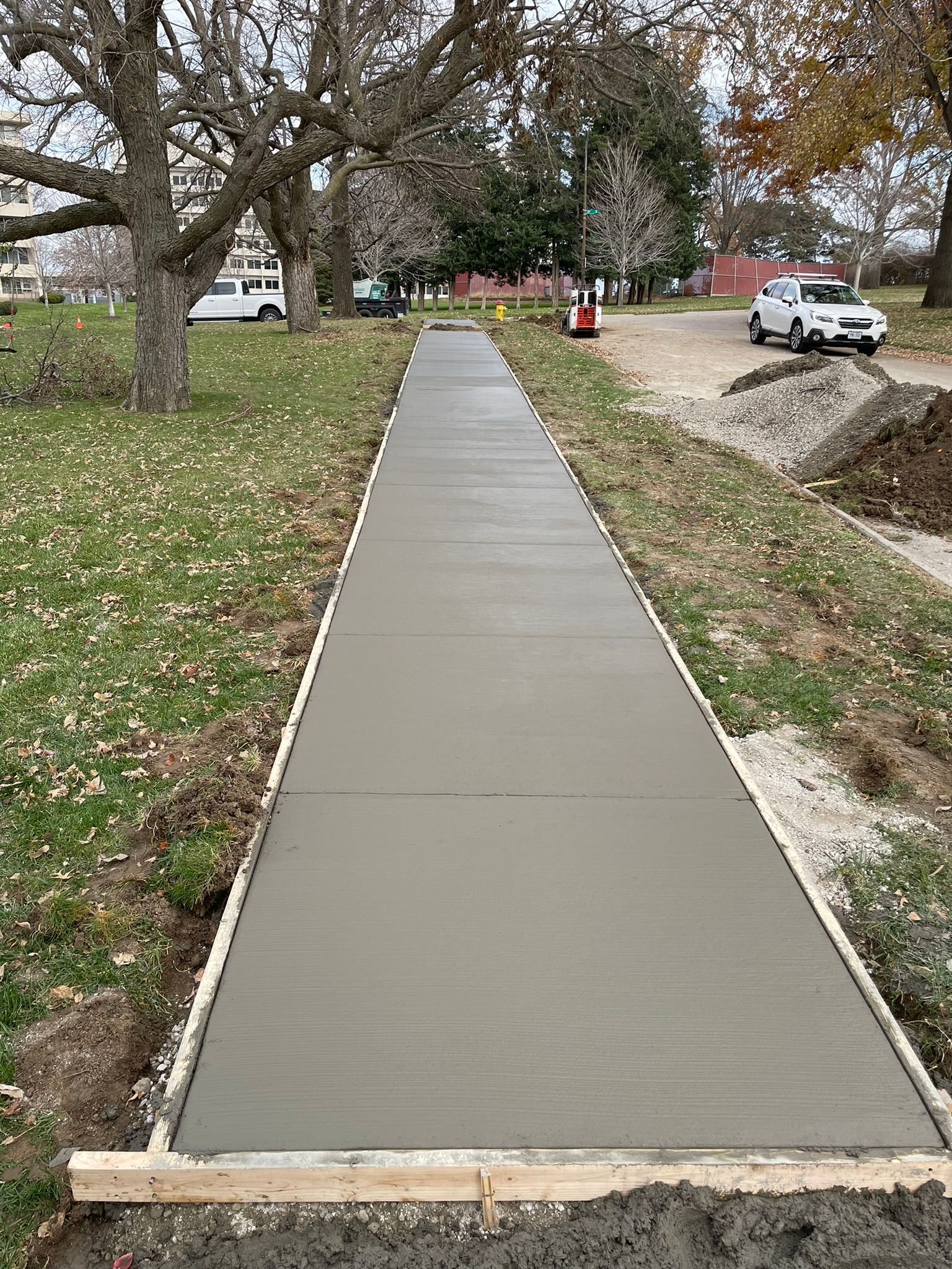A concrete walkway is being built in a park.