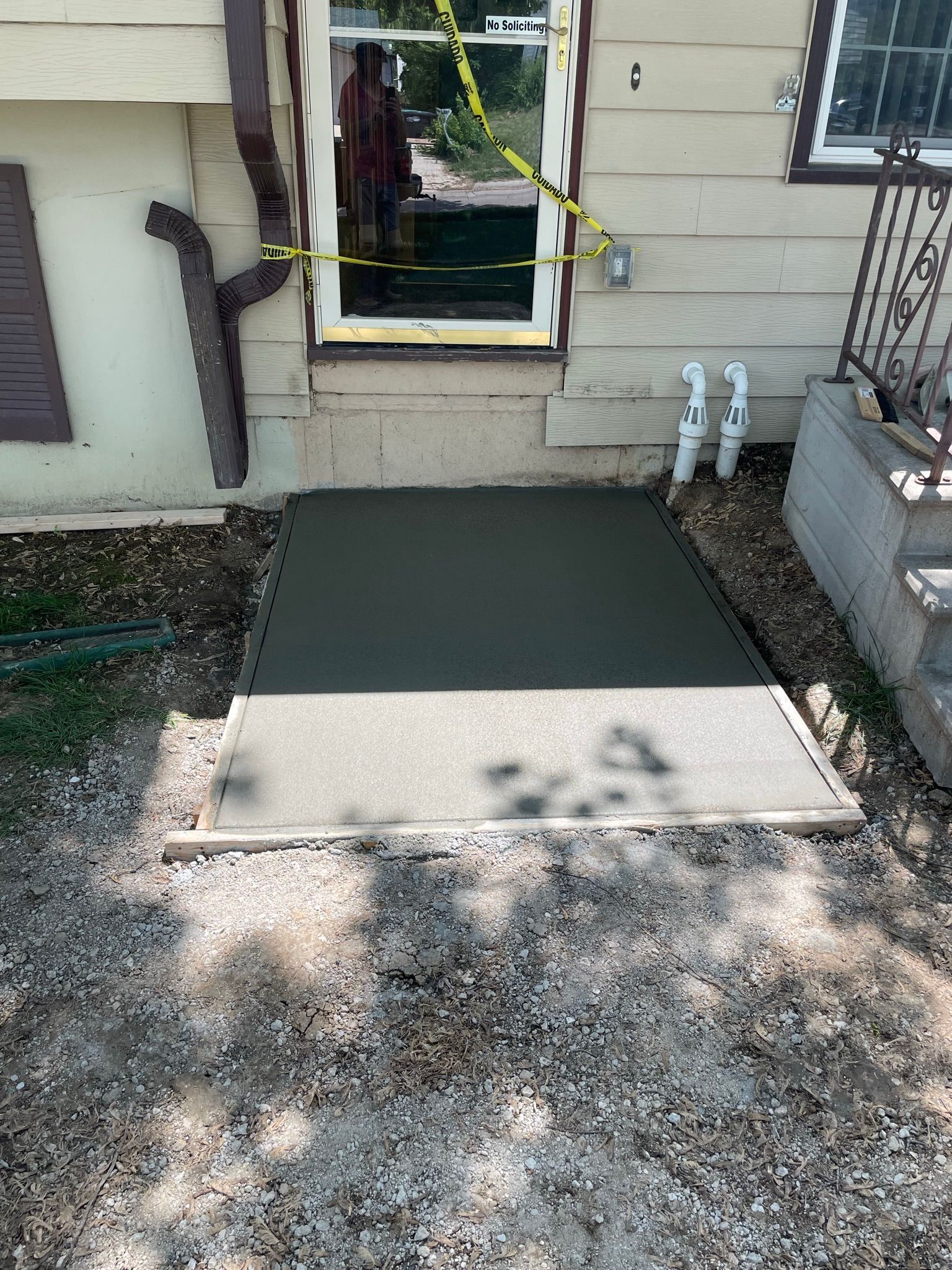 A concrete walkway is being built in front of a house.