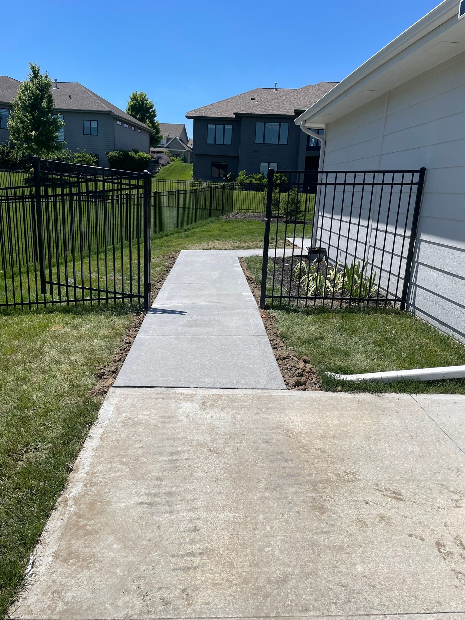 A concrete walkway leading to a house in a residential area.