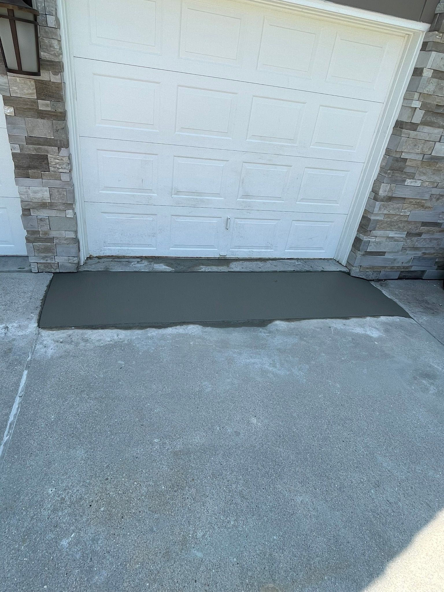A concrete ramp is being built in front of a garage door.