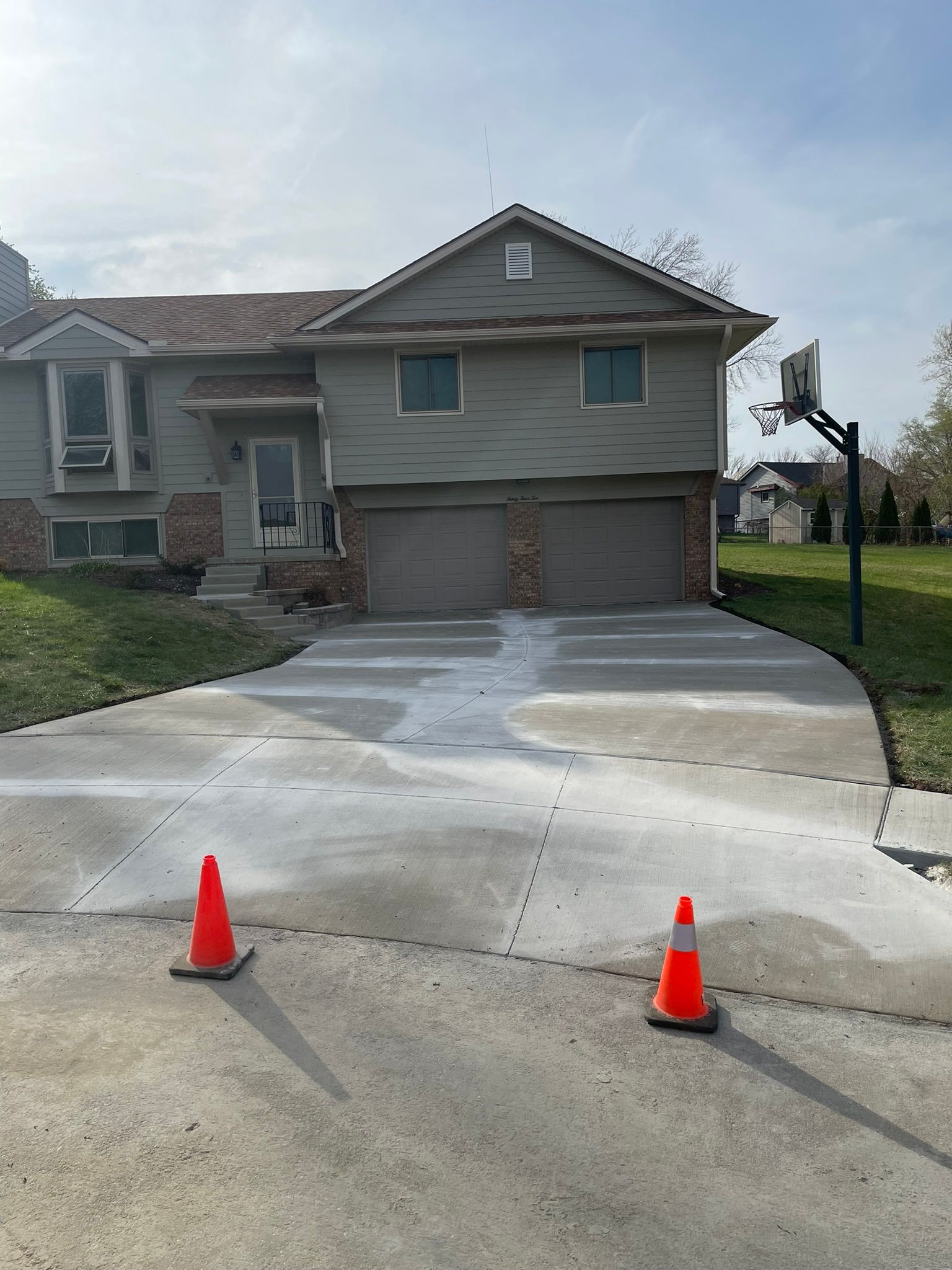 There are two orange cones in front of a house.