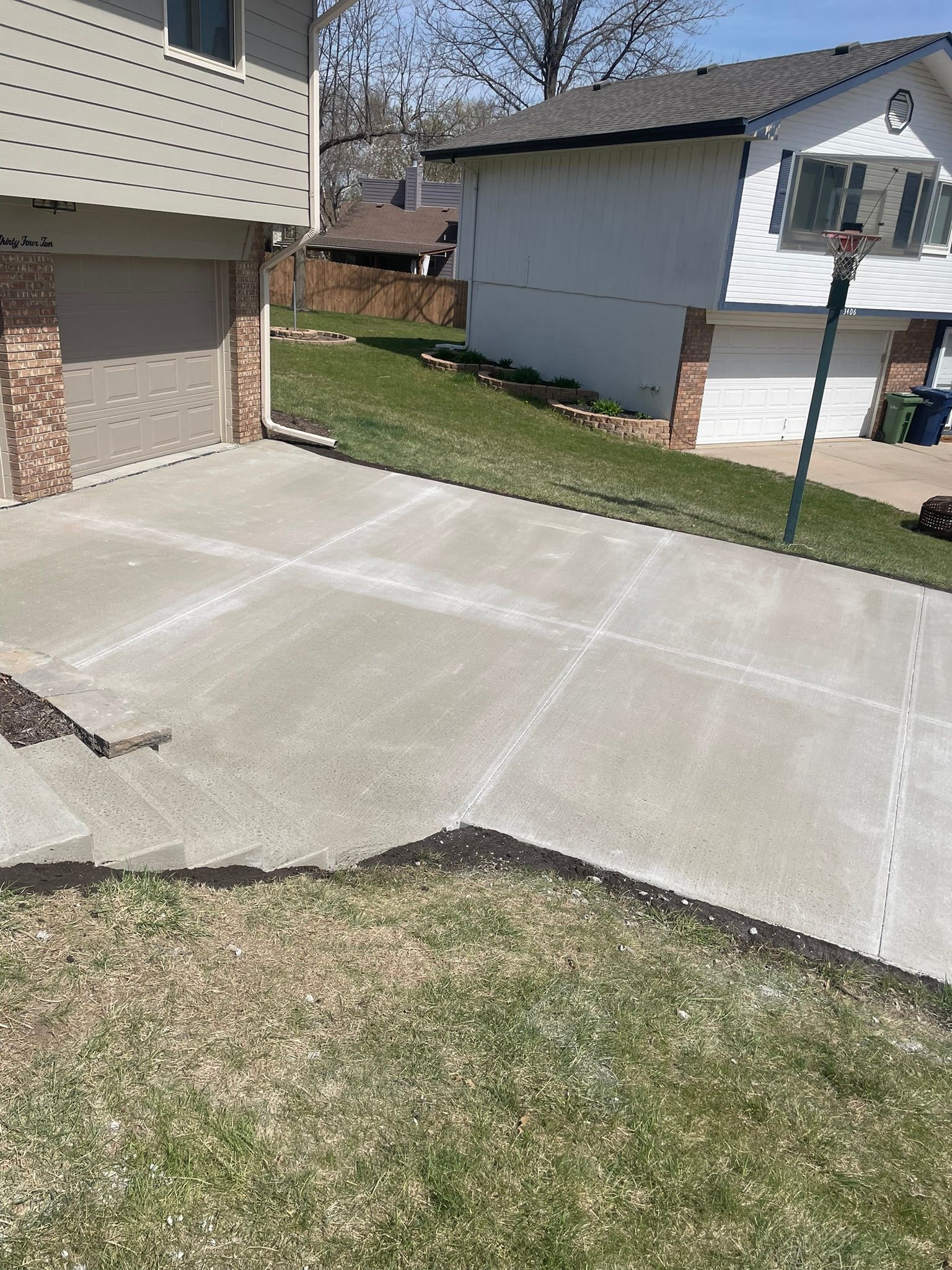 A concrete driveway leading to a house with a lawn in front of it.