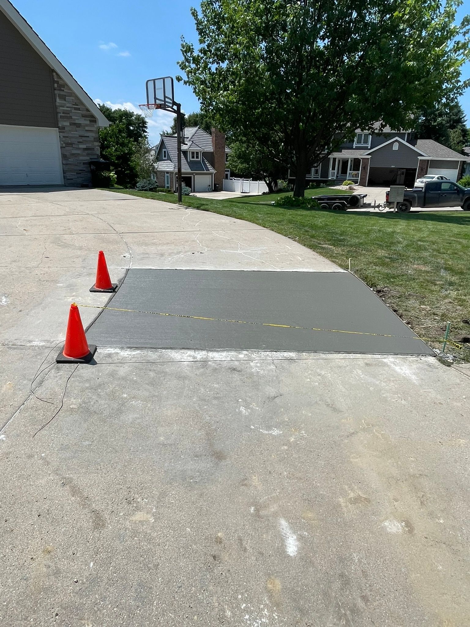 A basketball hoop is sitting on the side of a concrete driveway.