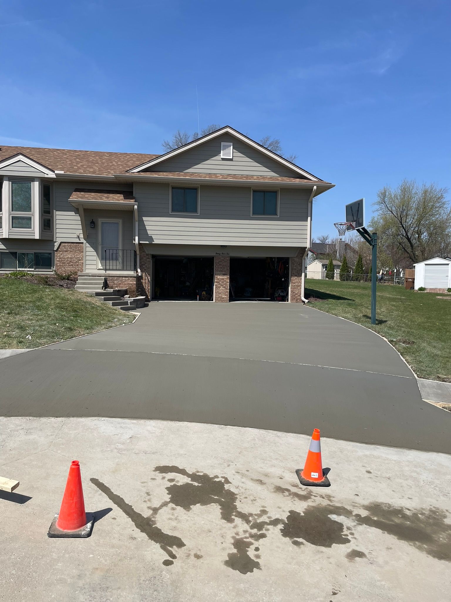 A concrete driveway is being installed in front of a house.