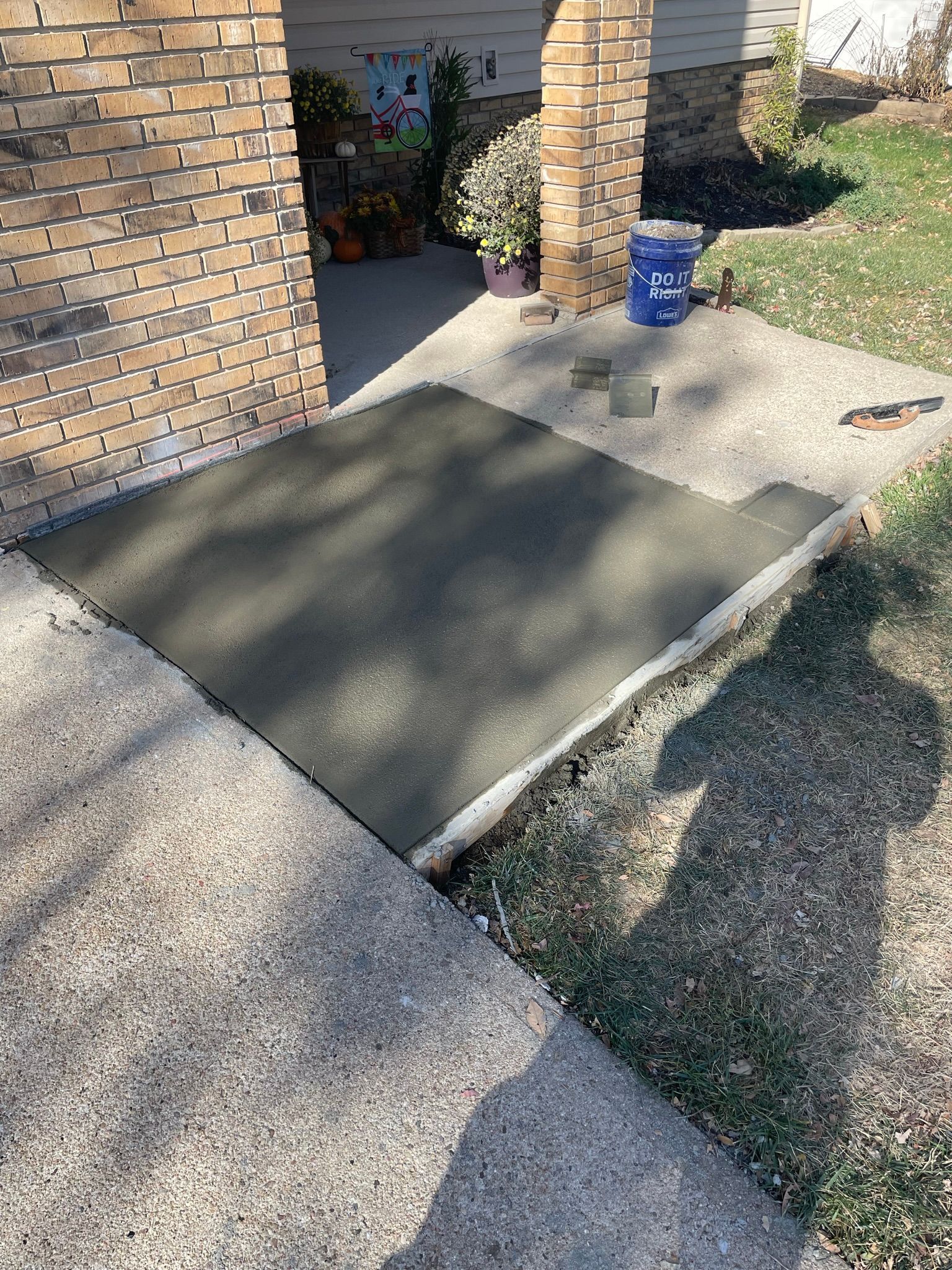 A concrete ramp is being built in front of a brick house.