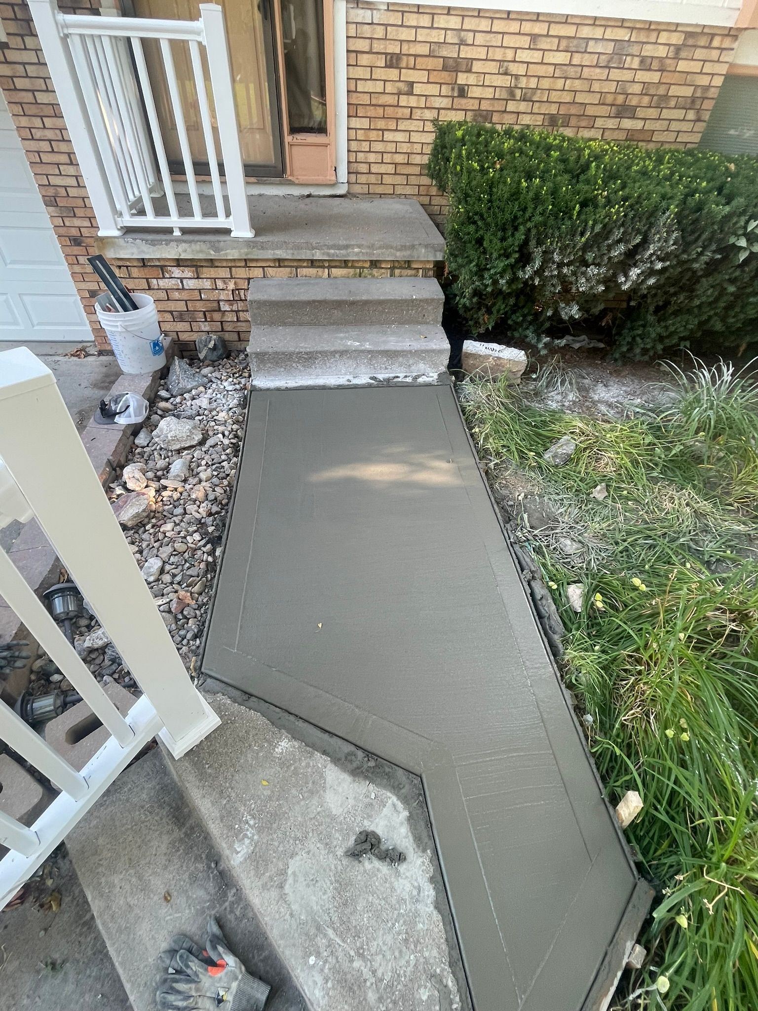 A concrete walkway is being built in front of a brick house.