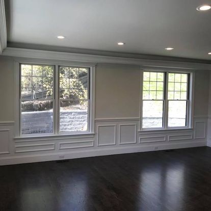 An empty living room with hardwood floors and lots of windows.