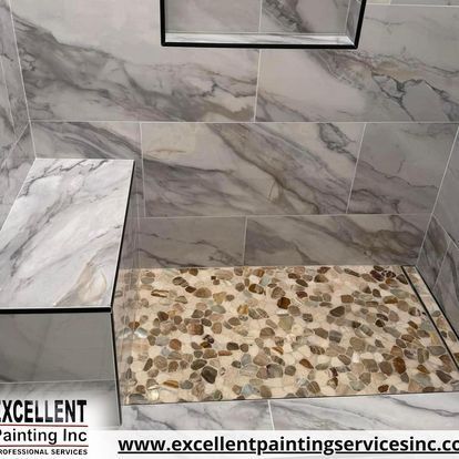 A shower stall with marble tiles and a pebble floor.