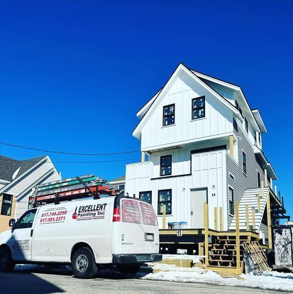 A white van is parked in front of a large white house.