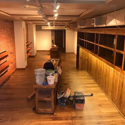 An empty room with wooden floors and a table with buckets on it.