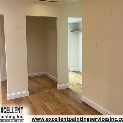 A hallway in a house with hardwood floors and beige walls.