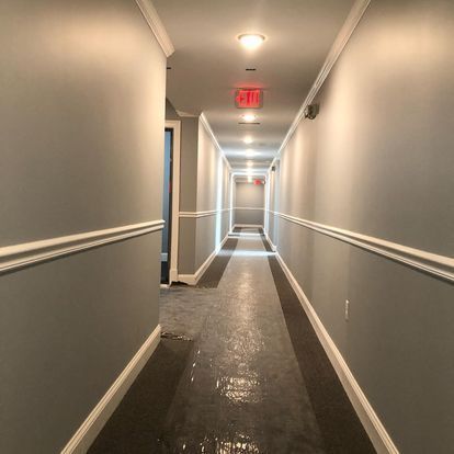 A long hallway with a red exit sign on the ceiling
