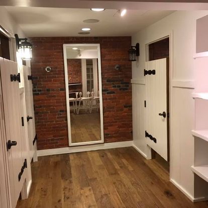 A hallway with a mirror on the wall and a brick wall.