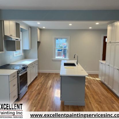 A kitchen with white cabinets, a stove, a sink and a window.