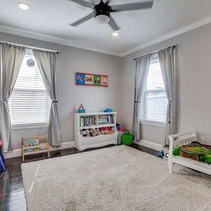 A bedroom with a ceiling fan, a bed, a bookshelf, and a rug.