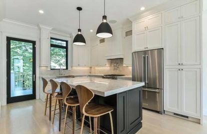 A kitchen with white cabinets and stainless steel appliances and a large island.